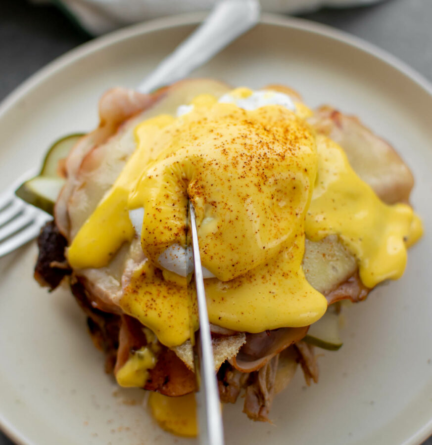 Cuban Eggs Benedict on a plate about to be cut into.