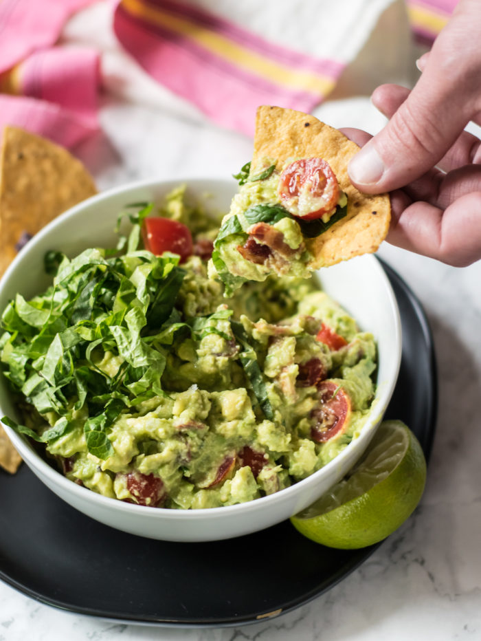 scooping guacamole with tortilla chip