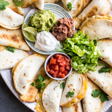Mini Green Chile Chicken Quesadillas with toppings, served on a platter.