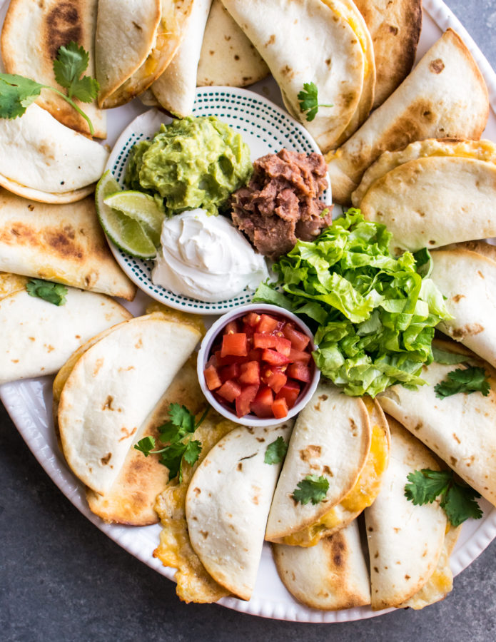 Mini Green Chile Chicken Quesadillas with toppings, served on a platter.