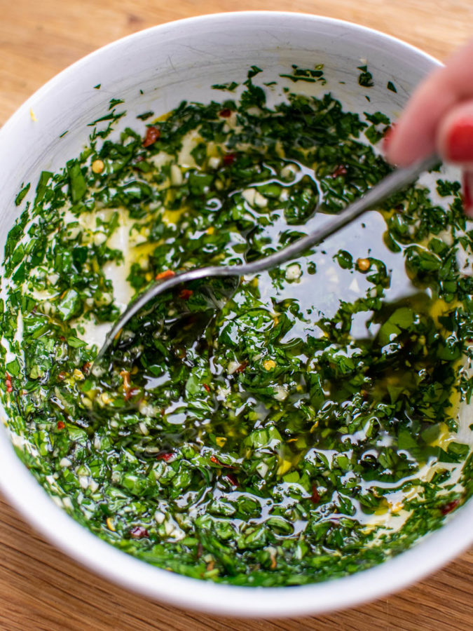 Chimichurri in a bowl being stirred.