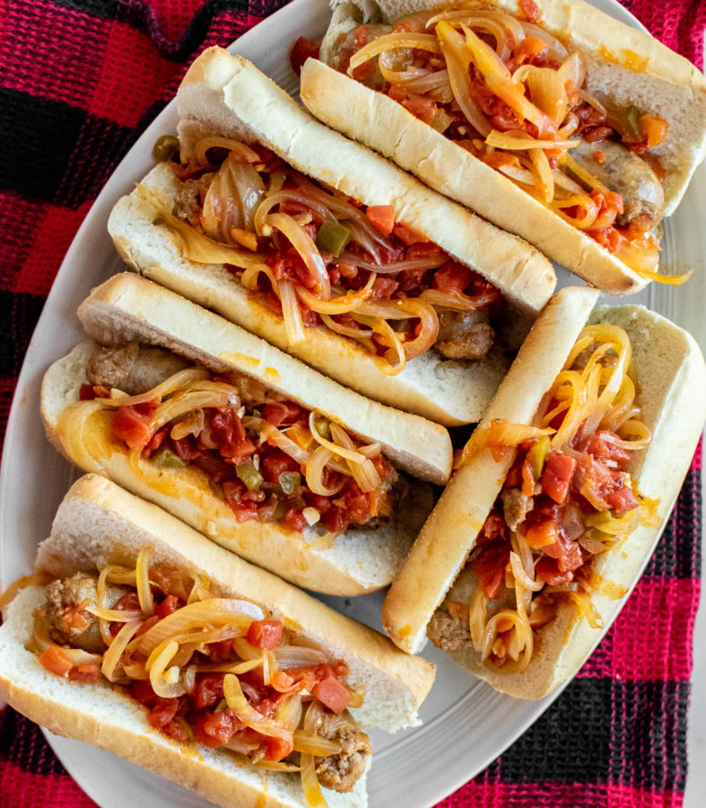 Italian Sausages with Spicy Tomato Sauce and Onions in buns on a serving platter.