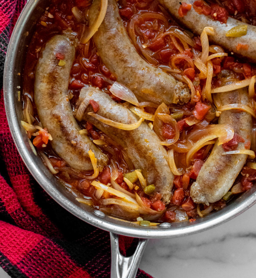 Italian Sausages With Spicy Tomato Sauce And Onions in a pan.