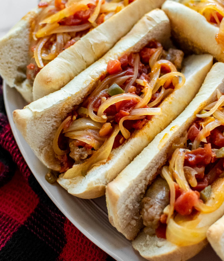 Italian Sausages With Spicy Tomato Sauce And Onions in buns on a serving platter.