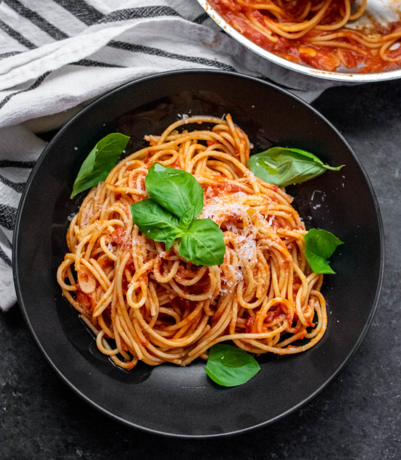 Pasta al Pomodoro in a bowl with fresh basil and cheese.