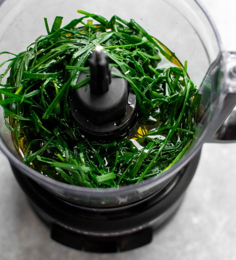 Chives, olive oil and salt in a food processor, ready to be blended.