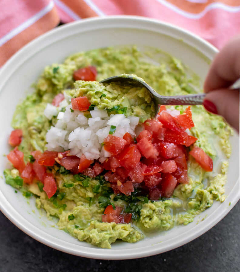 Easy Authentic Guacamole Recipe being mixed in a bowl.