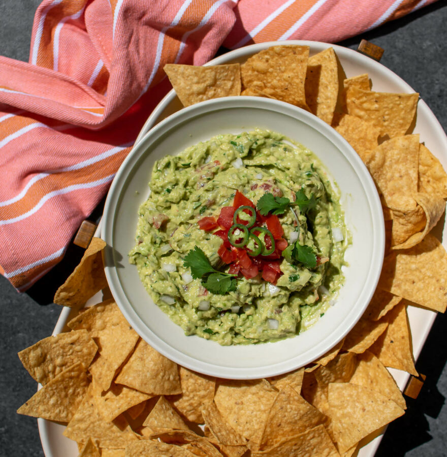 Easy Authentic Guacamole Recipe on a serving platter with tortilla chips.